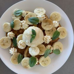 Fluffy American Diner Style mini pancakes with sliced banana, vanilla ice cream, fresh mint, whipped cream and maple syrup