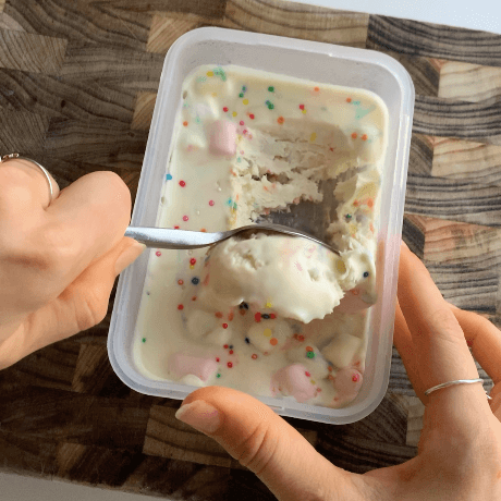 A tub of marshmallow sprinkle ice cream being scooped