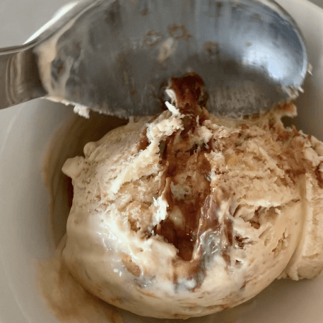 A bowl of Chocolate Peanut Butter Ice Cream being released from the ice cream scoop