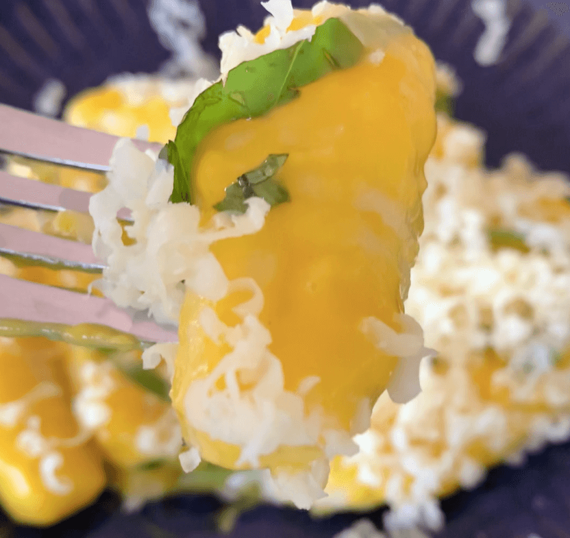 a pile of gnocchi coated in a creamy pumpkin sauce covered in strips of basil and grated cheese on a dark blue plate