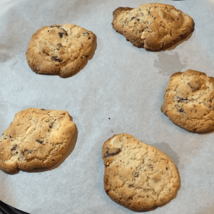 A tray of unevenly shaped chocolate chip cookies