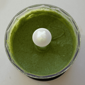 A food processor filled with a bright green puree