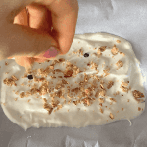 Yoghurt spread on a tray being sprinkled with granola