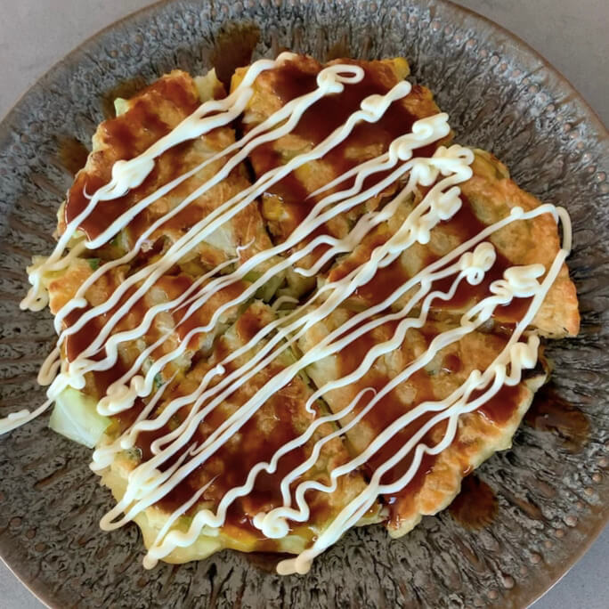 Okonomiyaki covered in mayo and okonomiyaki sauce