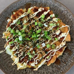 Okonomiyaki covered in mayo, okonomiyaki sauce, furikake and spring onion