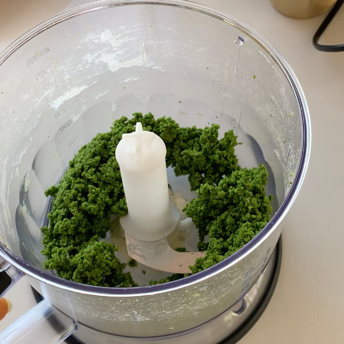 Bright green pici pasta dough in a food processor