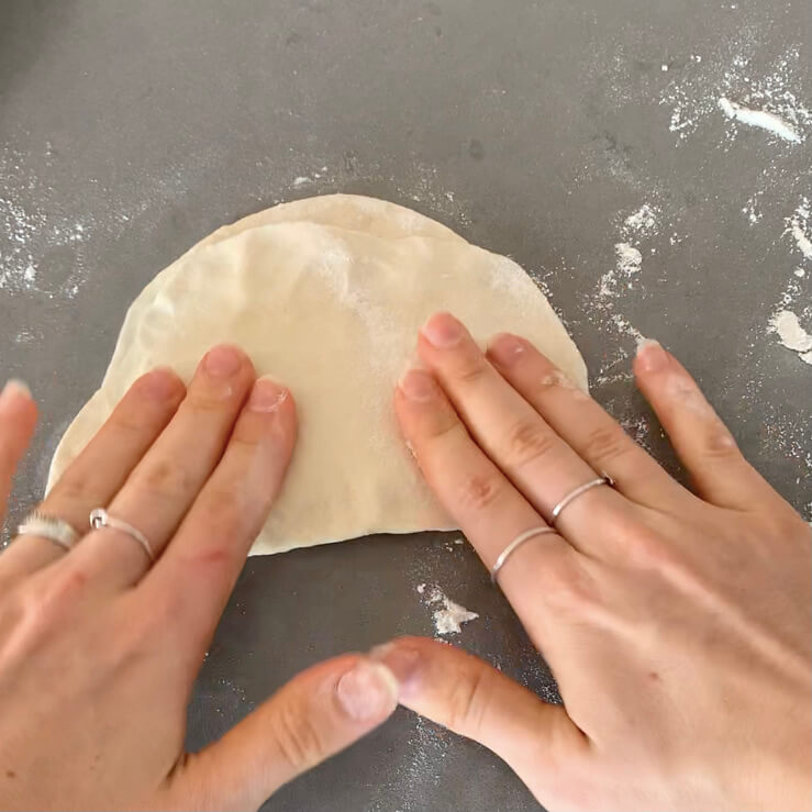 Dough on a bench being pushed with hands