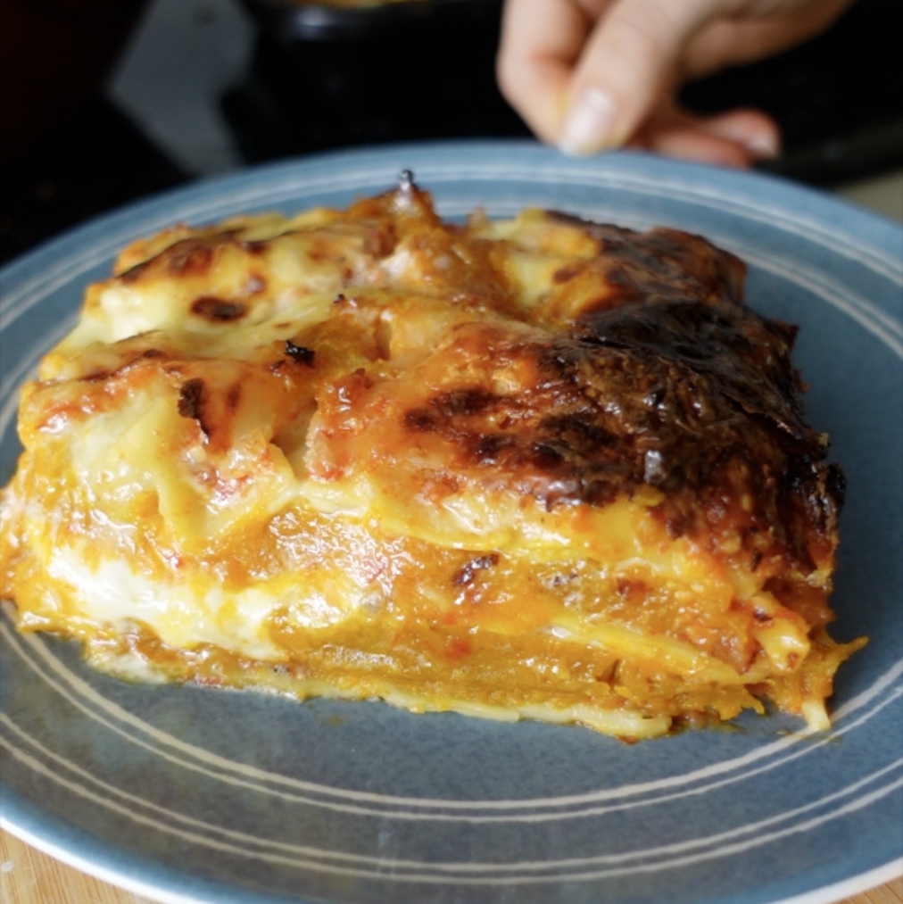 A slice of pumpkin and ricotta lasagne taken from the side to see the layers on a blue plate