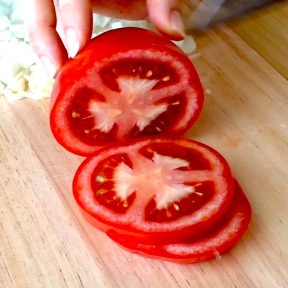 slicing a ripe truss tomato on a wooden chopping board