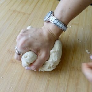 Kneading dough by hand on a wooden bench top