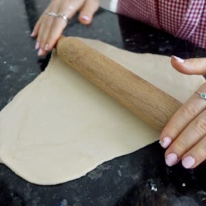 rolling out pastry with a rolling pin on a black bench