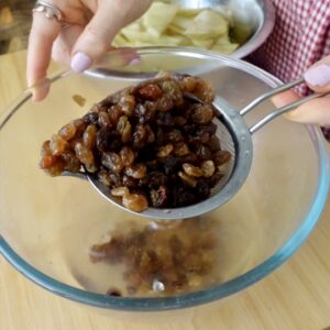 draining soaked raisins in a sieve over a glass bowl