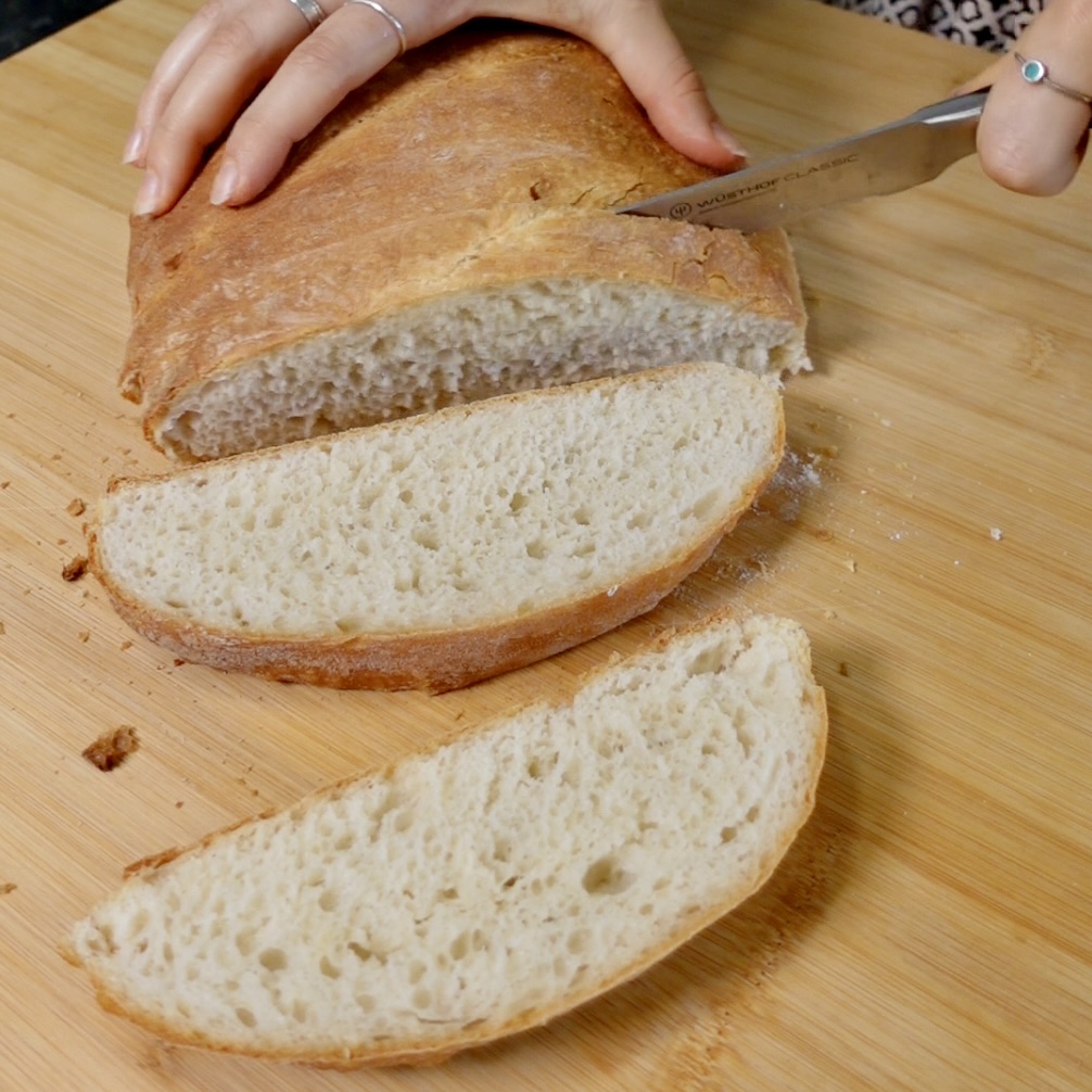 A loaf of bread being sliced in to